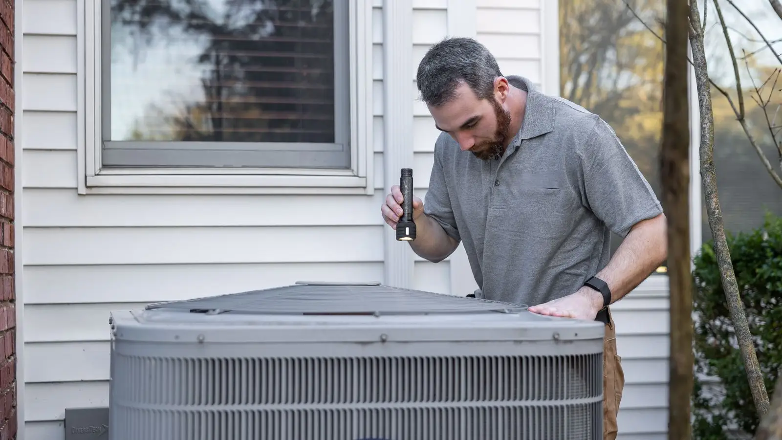 Technician cleaning outdoor HVAC condenser coil during a DUCTS maintenance visit in Birmingham AL