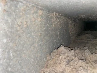 Air duct trunk with about twenty years of dust and insulation buildup before cleaning, Birmingham metro home
